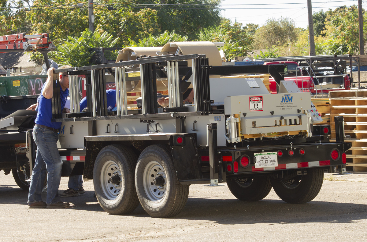 A service technician examines an NTM SSH™ MultiPro roof panel machine outdoors