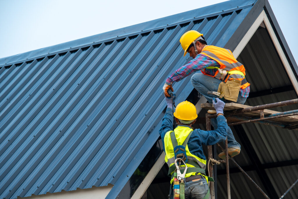 Roofer using air or pneumatic nail gun and installing metal roof tile on top roof,Builder Working On Roof Of new building.