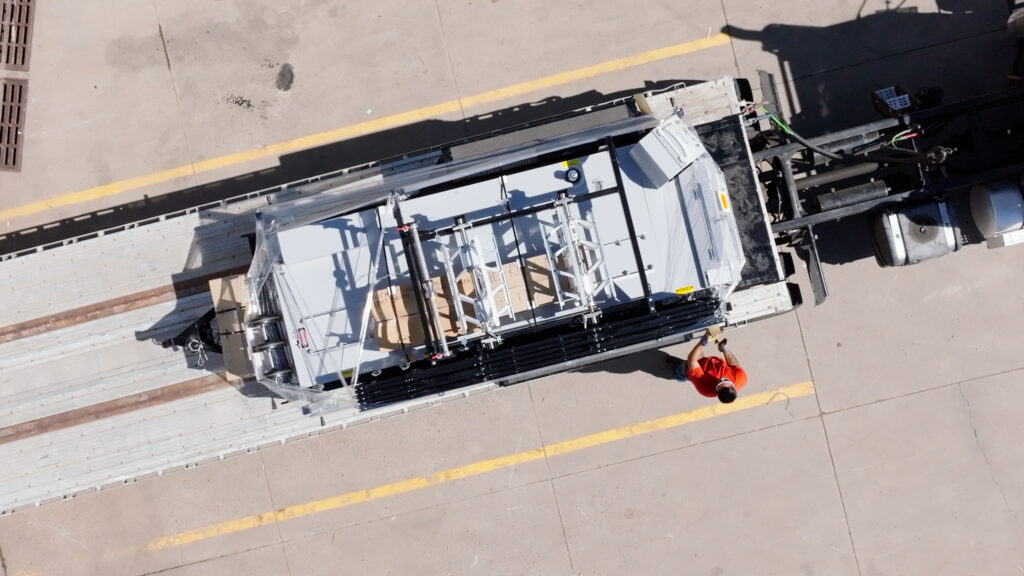 Unloading a machine from a flatbed truck.