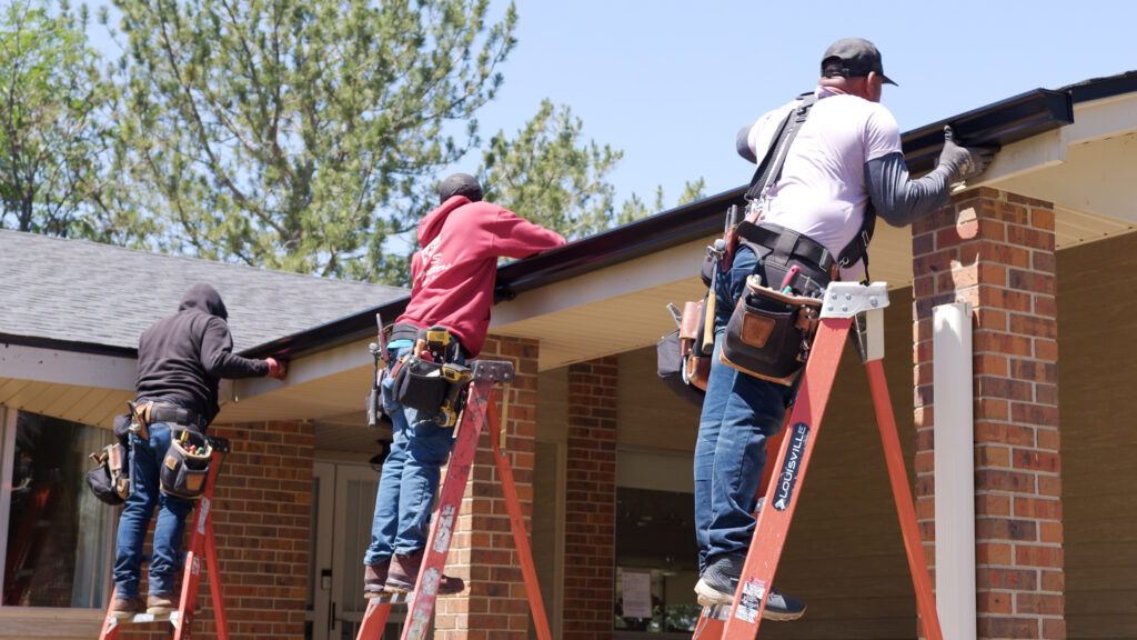 three installers hanging gutter