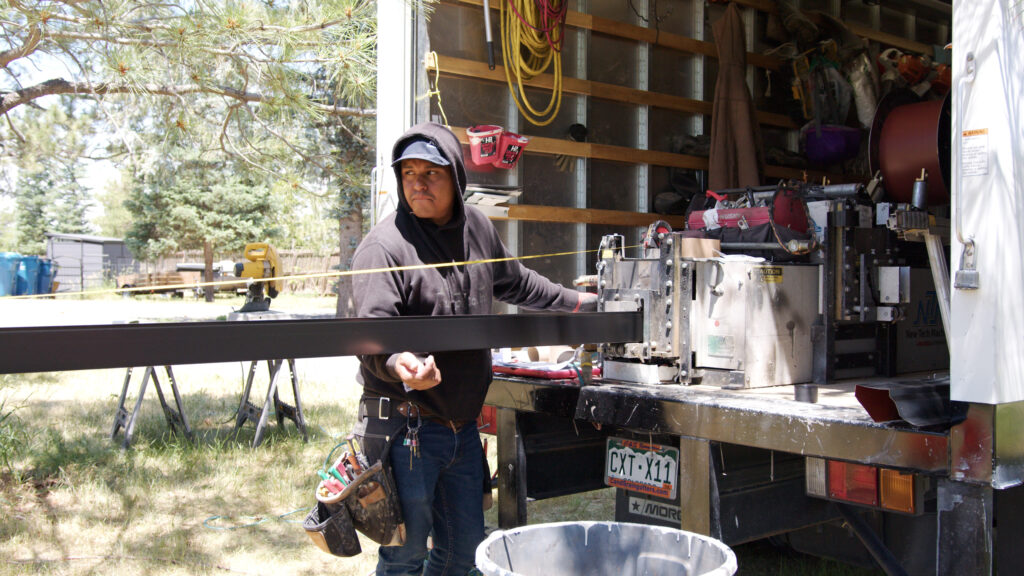 Running gutter from a portable gutter machine in the back of a covered truck.