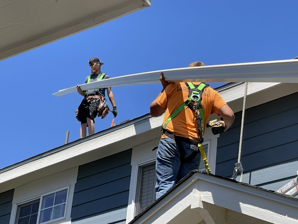 Installing seamless gutters onto a house.